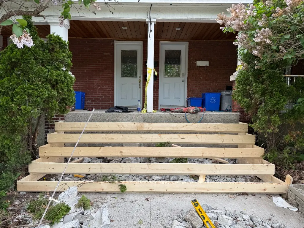 Wooden forms for five new concrete steps set over a gravel base at a duplex porch