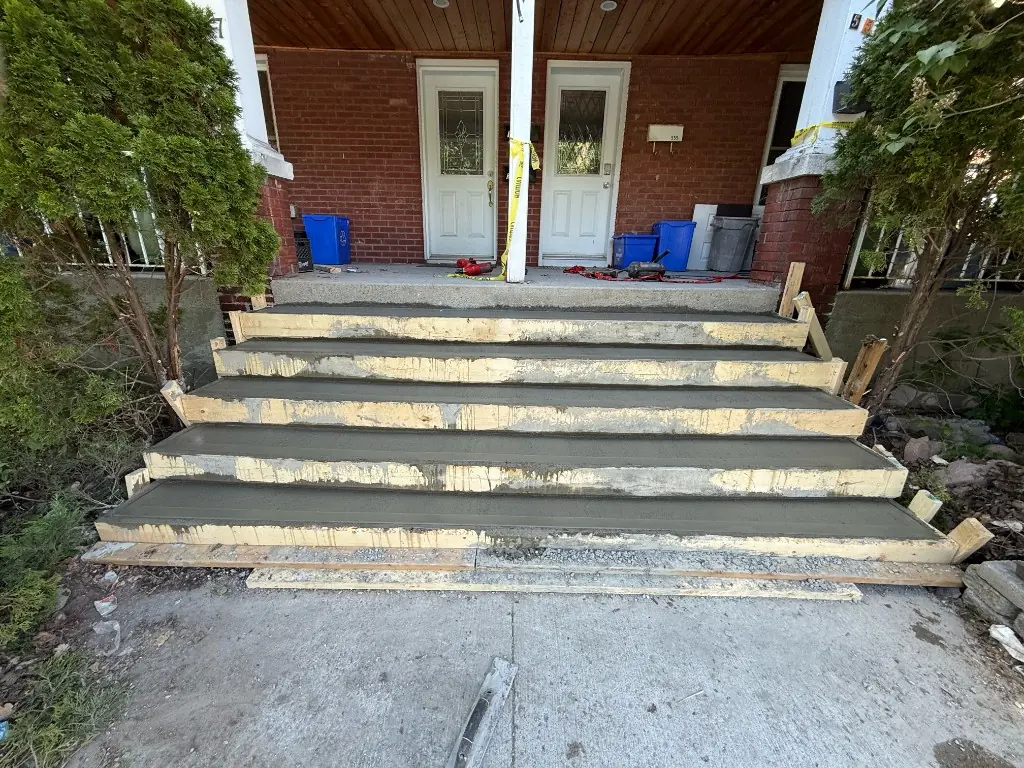 Freshly poured concrete steps still in their forms at a duplex porch