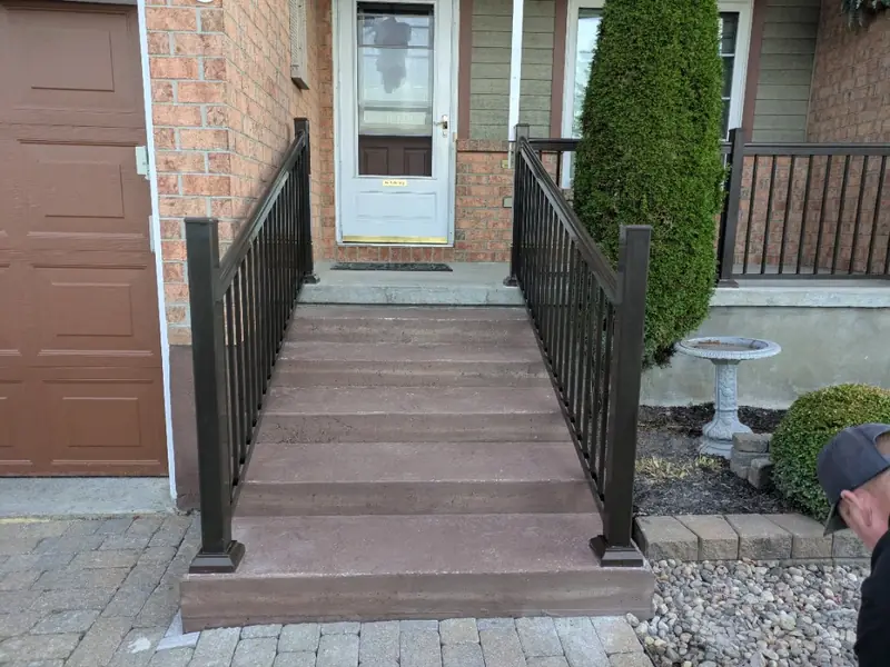 Front steps with new black aluminum railings beside a garage