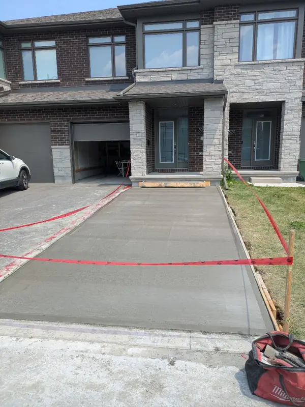 Freshly poured concrete driveway in front of a townhouse, taped off while it cures