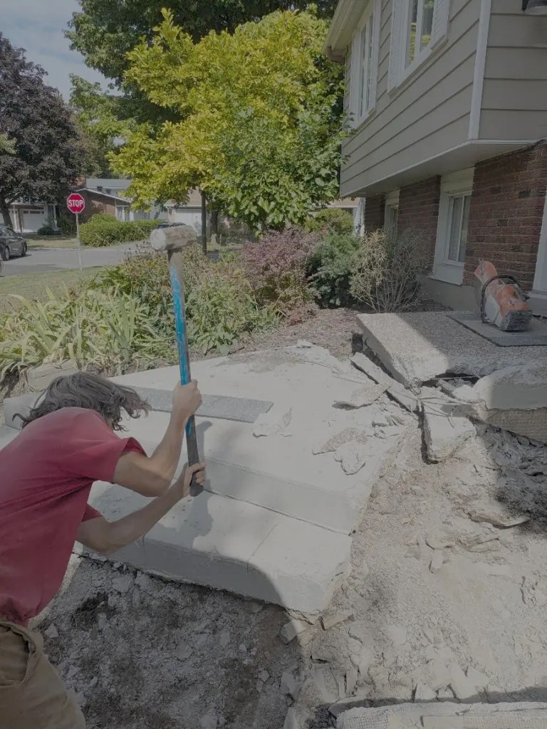 Old concrete steps being broken out with a sledgehammer