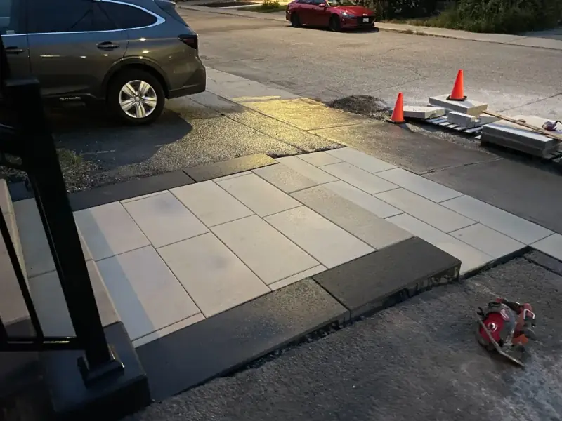 Large-format slab walkway with a dark border being finished at dusk