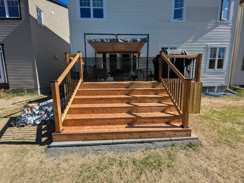 Wide wood deck stairs with wood posts and rails and black metal balusters